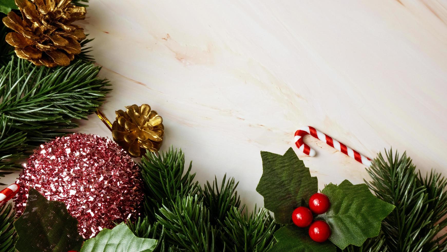 hojas de pino verde, adornos navideños rosas y bastones de caramelo sobre fondo de mármol suave, adornos navideños en color rosa brillante y elegante. concepto de navidad simple y creativo. foto