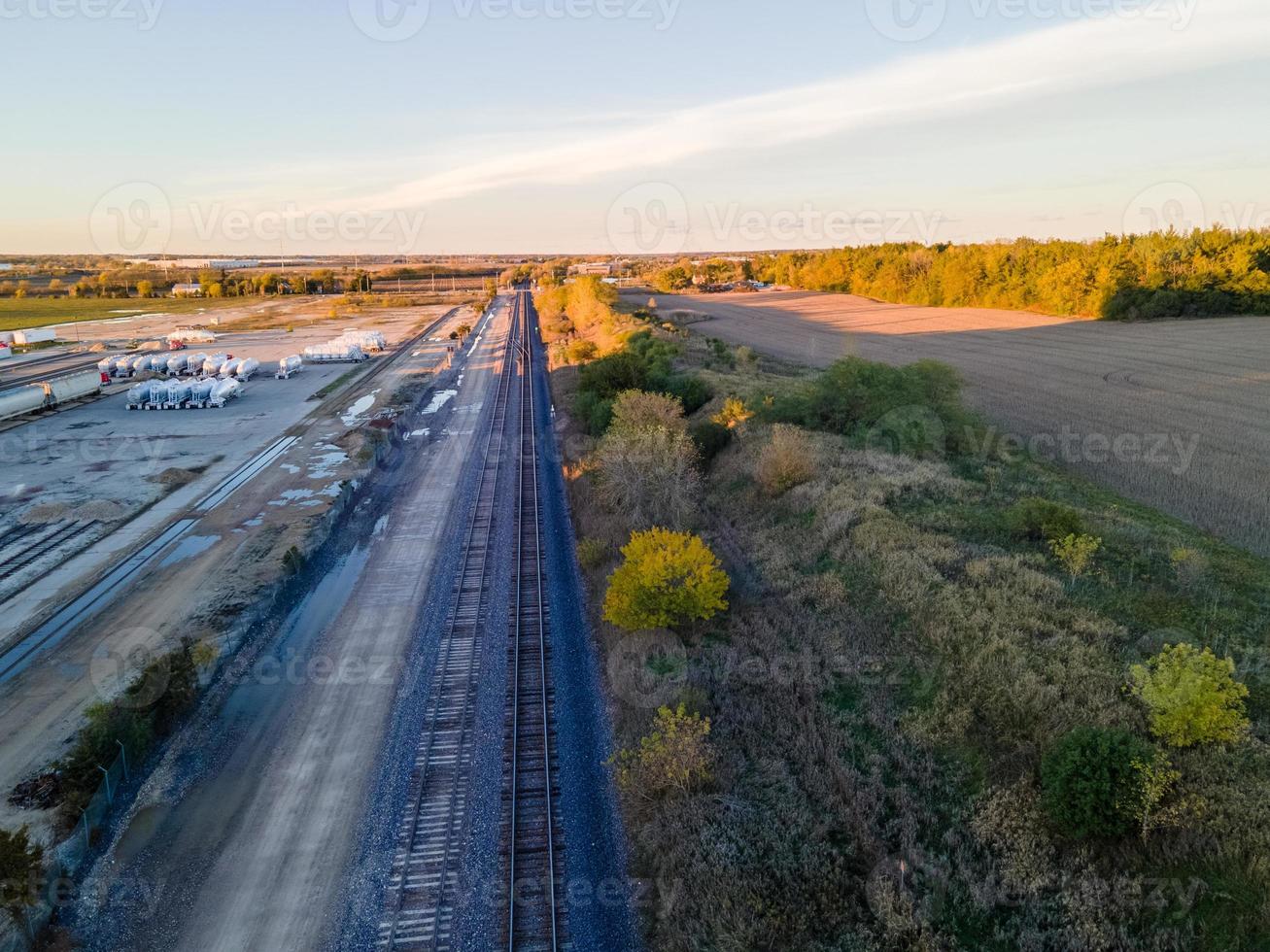 aerial view of farm field and rail transport merging at sunset photo