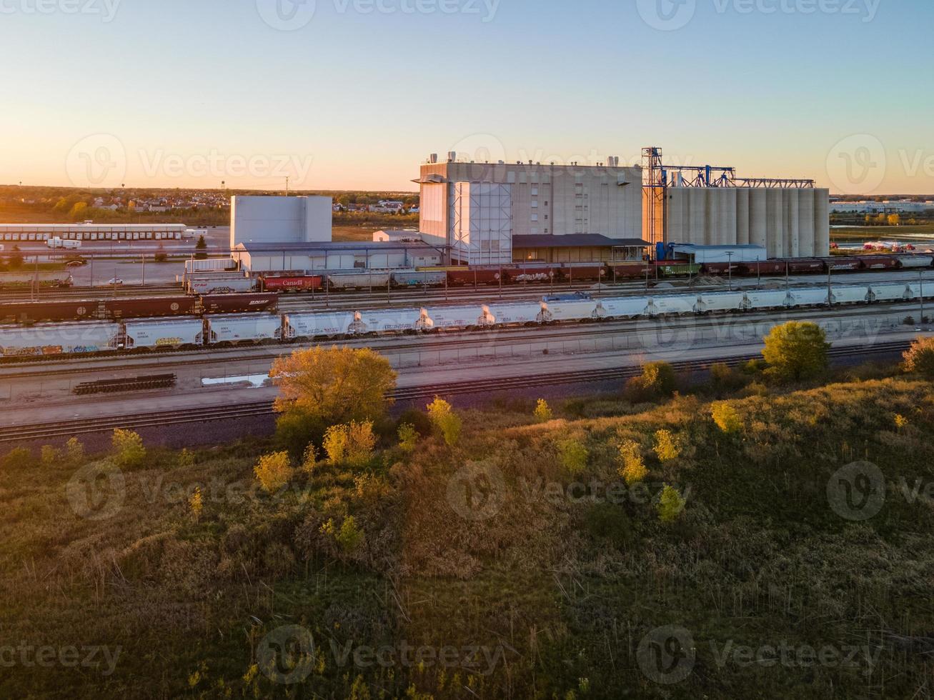 Estación de carga ferroviaria industrial con árboles y vehículos. foto