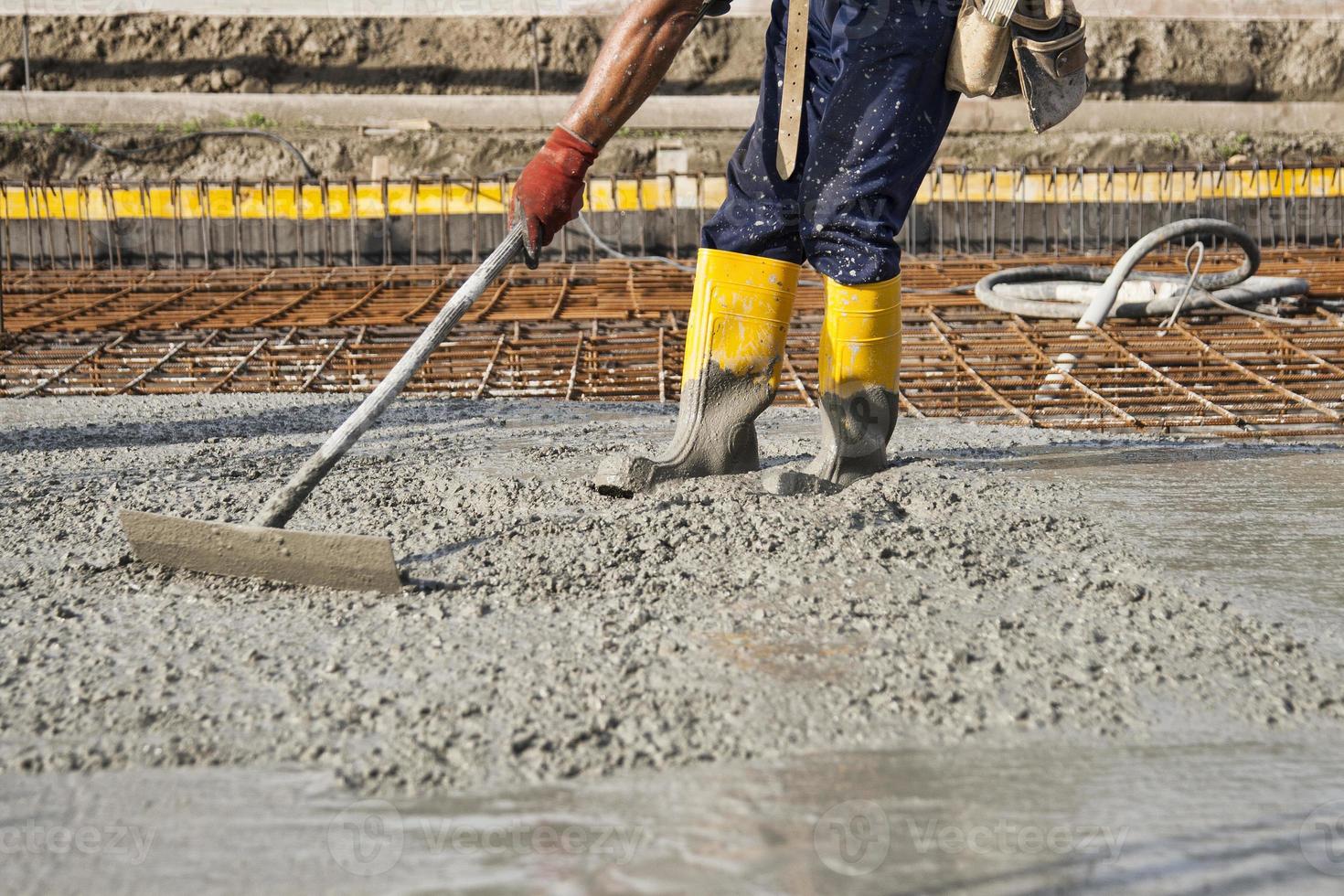 bricklayer who level the freshly poured concrete to lay the foundations of a building photo