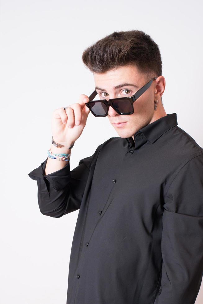 Portrait of an attractive young man wearing sunglasses. Studio shot, model looking to the camera. photo