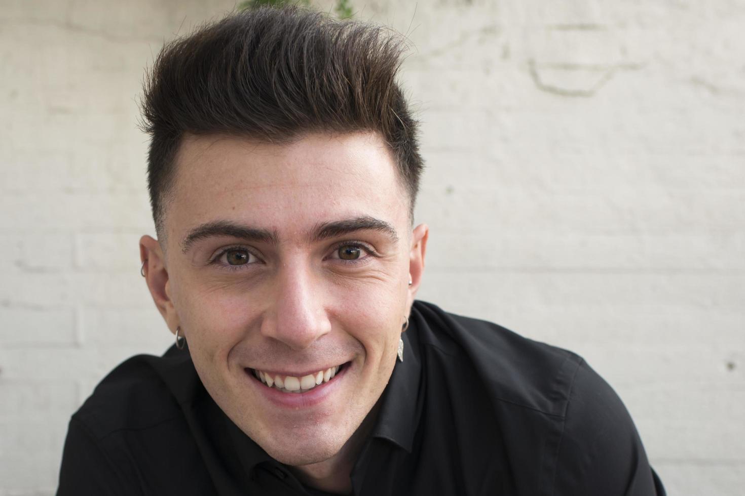 Close up of an attractive young man, smiling and looking at camera. Outdoors, photo