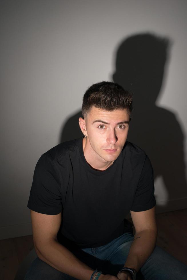 Studio shot of a handsome young man and his shadow behind  him. photo