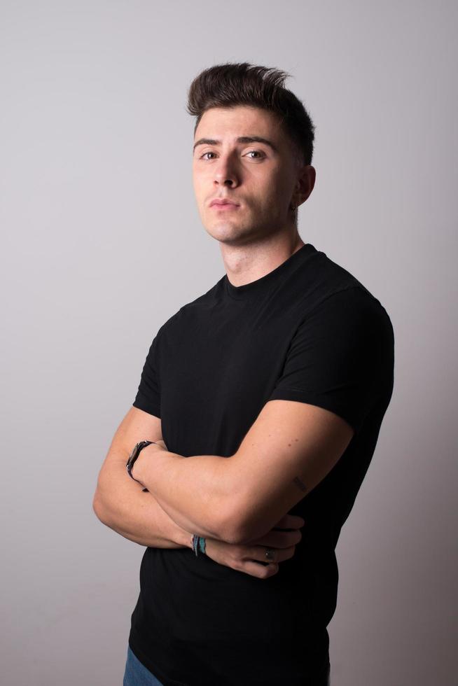 retrato de estudio de un atractivo joven vestido de negro. brazos cruzados. foto