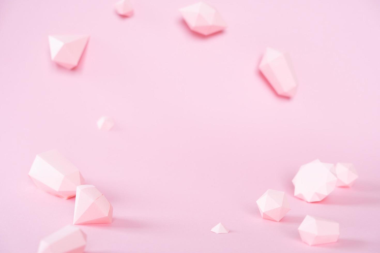 una variedad de piedras preciosas facetadas, hechas de papel sobre un fondo rosa. foto