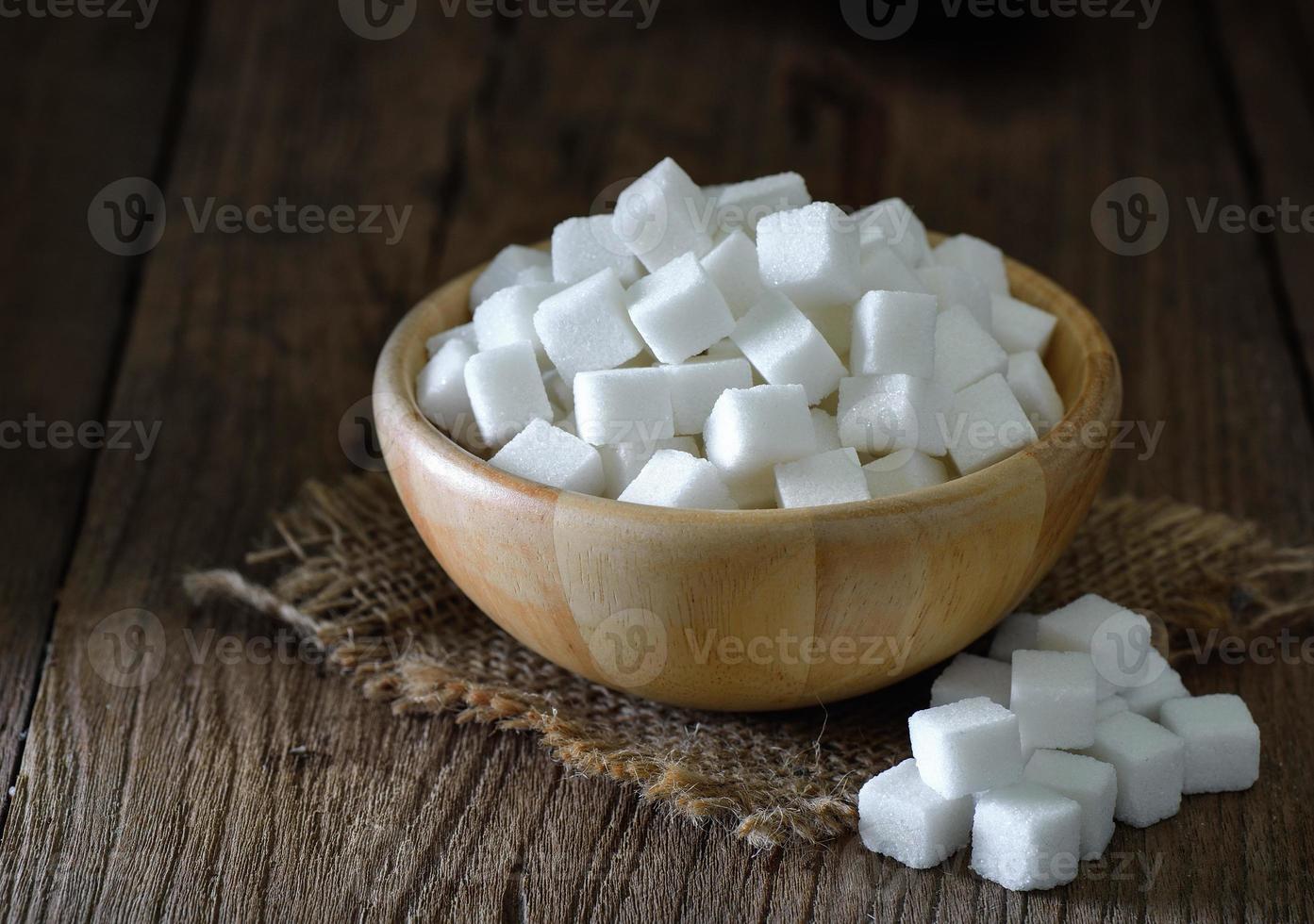 Sugar cubes in wood bowl on wood table photo