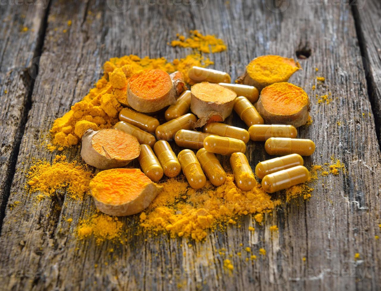 Turmeric powder and turmeric capsules on wooden background photo