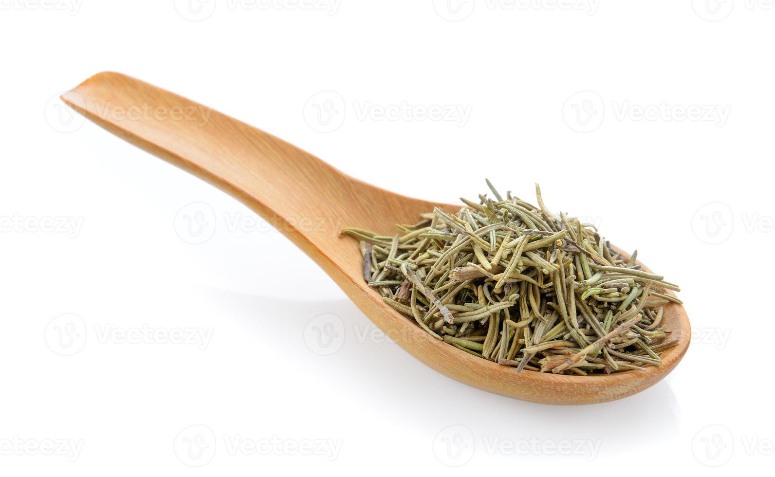 Dried rosemary leaves in wooden spoon over white background photo
