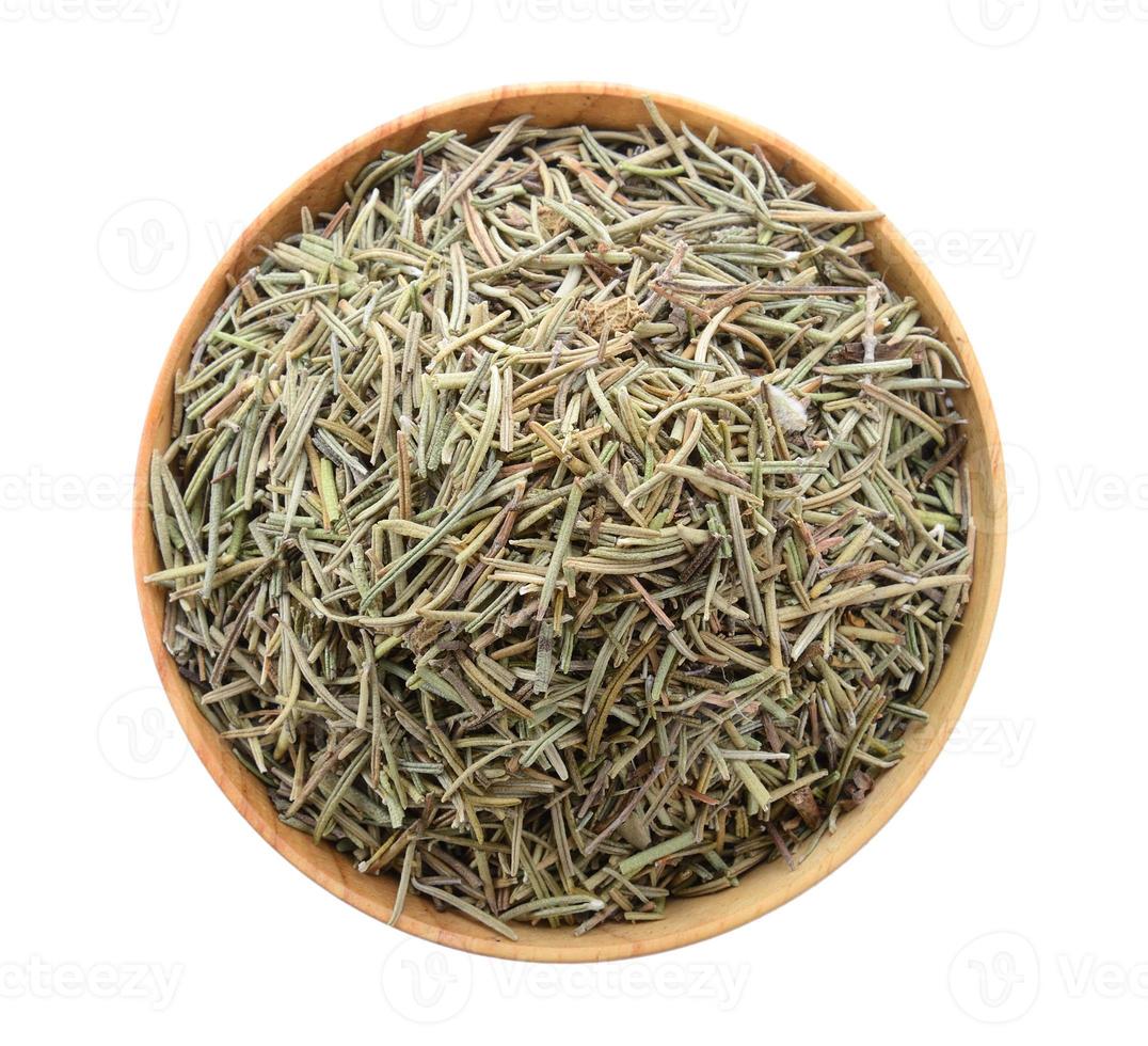 Dried rosemary leaves in wooden bowl over white background photo