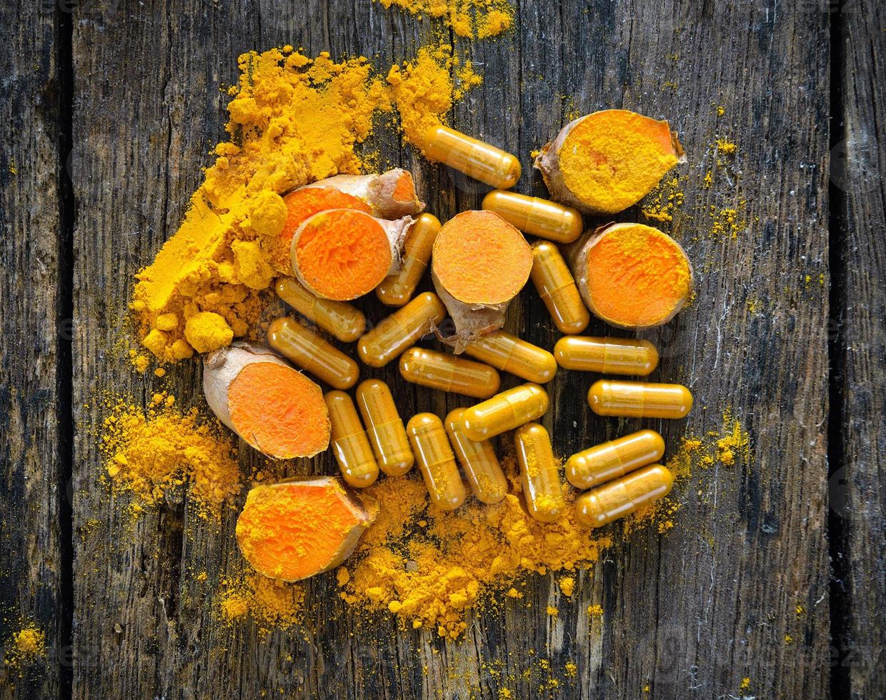 Turmeric powder and turmeric capsules on wooden background photo