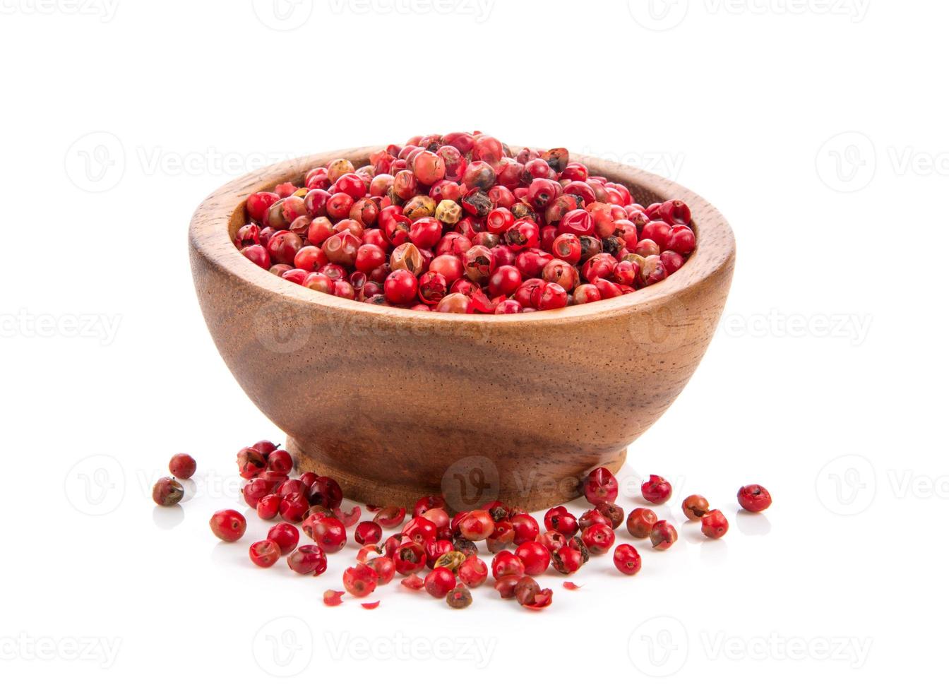 dried pink peppers in wood bowl isolated on white background photo