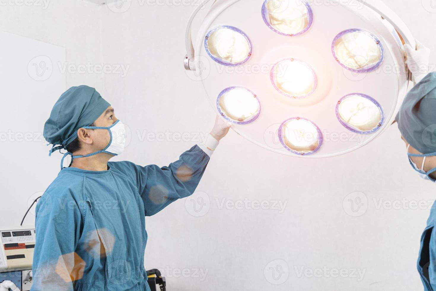 Asistente de cirujano preparando lámparas quirúrgicas en el quirófano foto