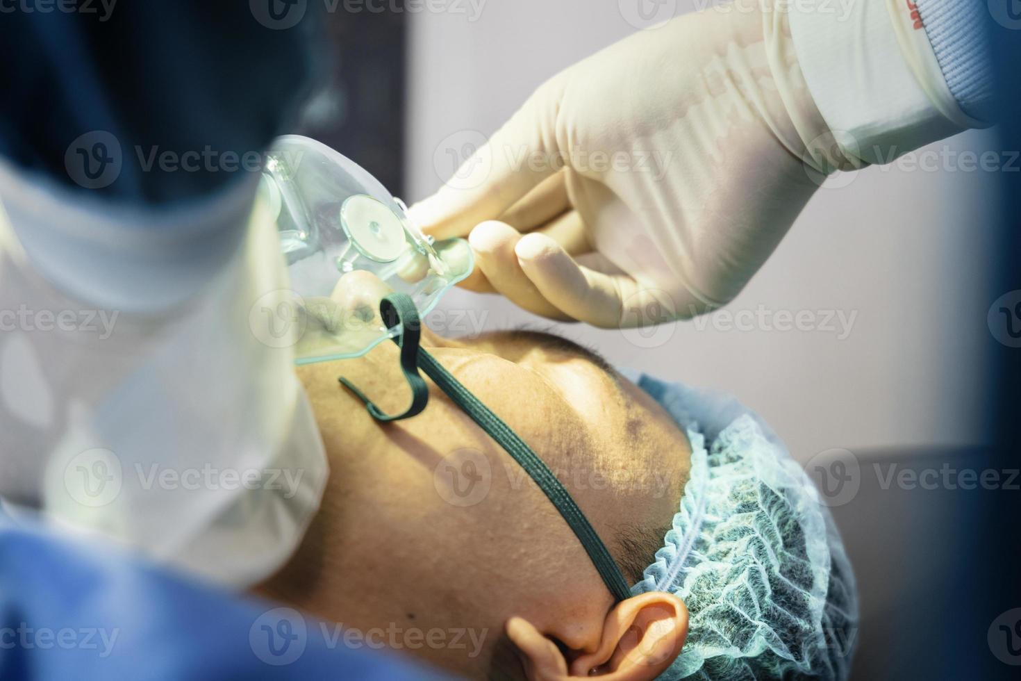 El cirujano asistente puso al paciente en una máscara de oxígeno y ventilador en preparación para la cirugía. foto