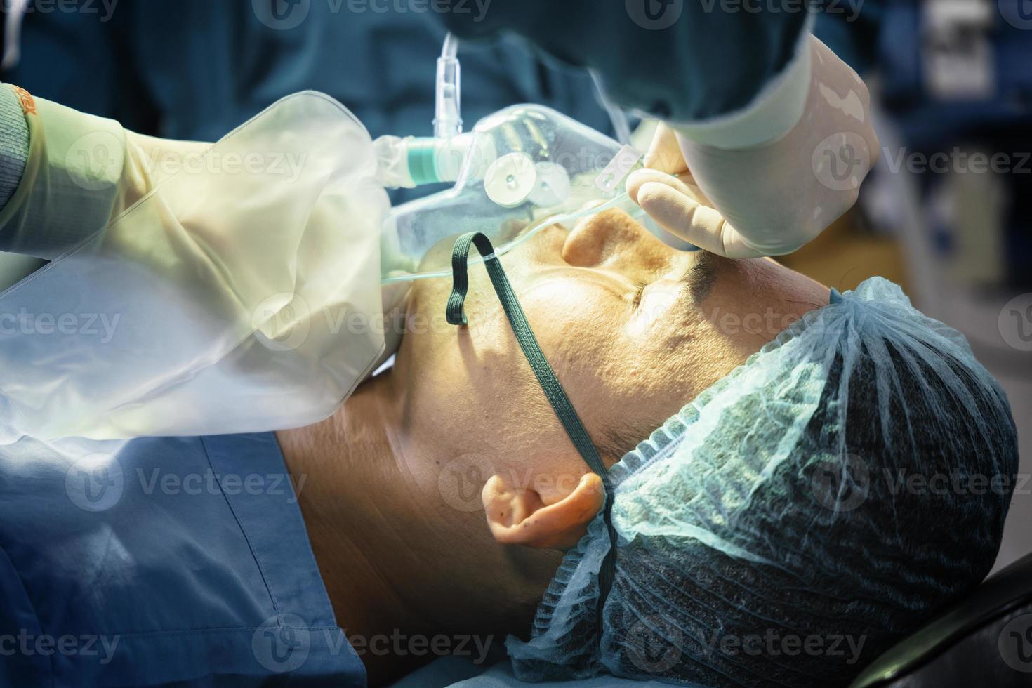 assistant surgeon put the patient on a ventilator-oxygen mask in preparation for surgery. photo