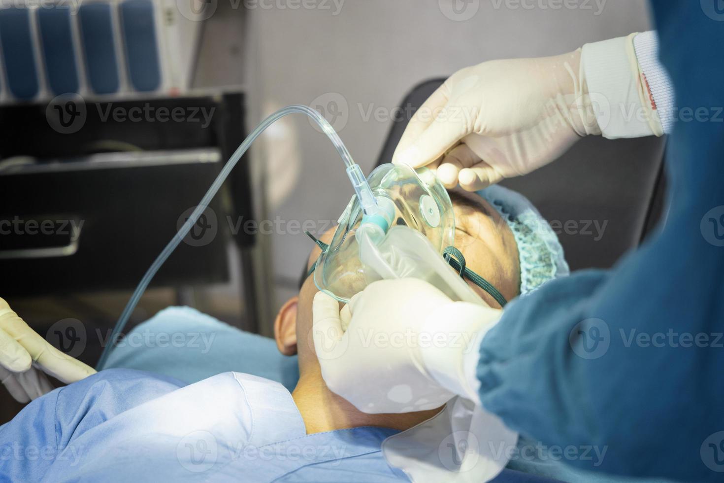 El cirujano asistente puso al paciente en una máscara de oxígeno y ventilador en preparación para la cirugía. foto