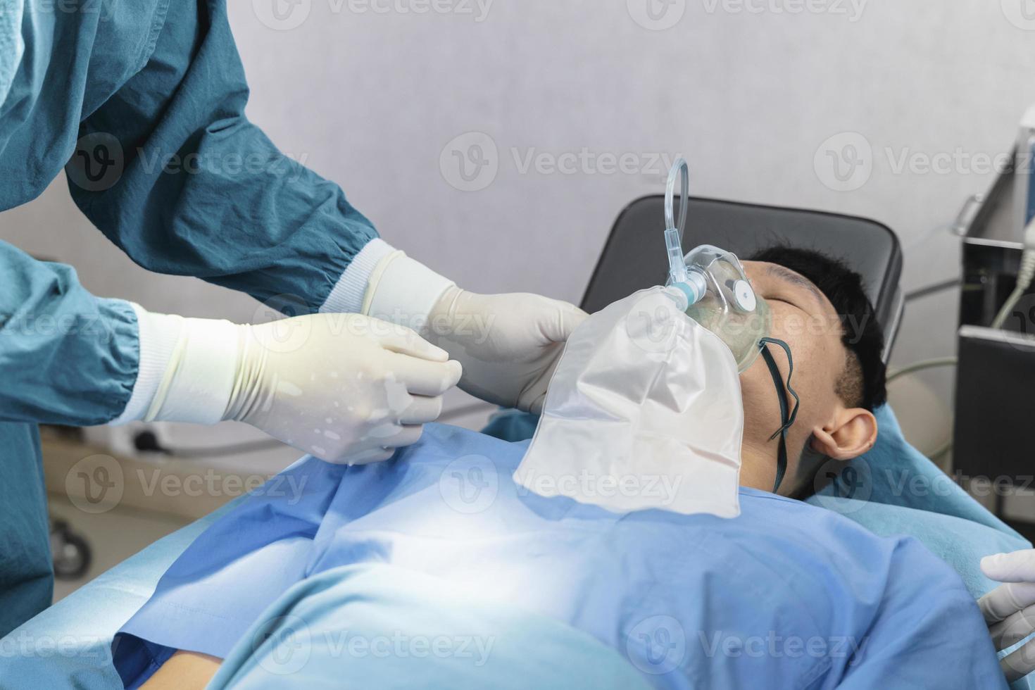 El cirujano asistente puso al paciente en una máscara de oxígeno y ventilador en preparación para la cirugía. foto