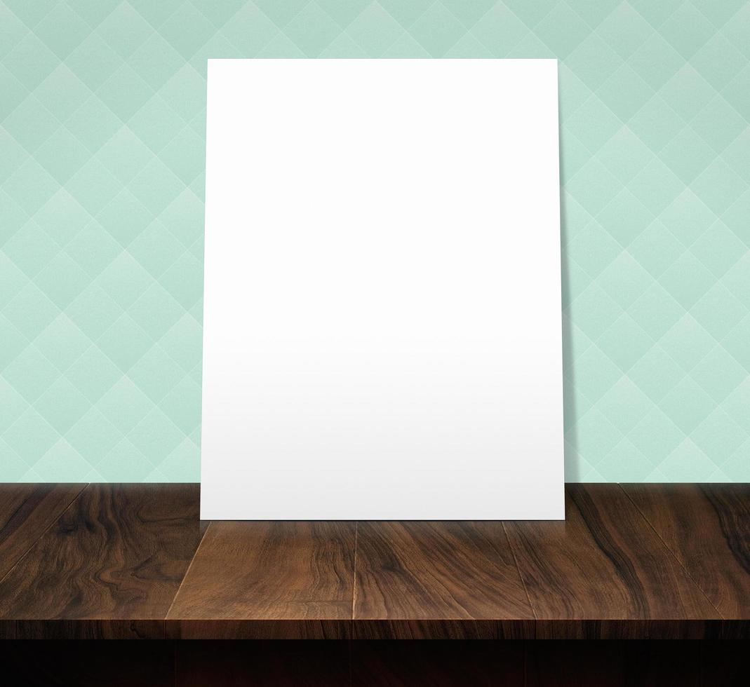 The white poster on a wooden table with a light green diamond pattern wall photo