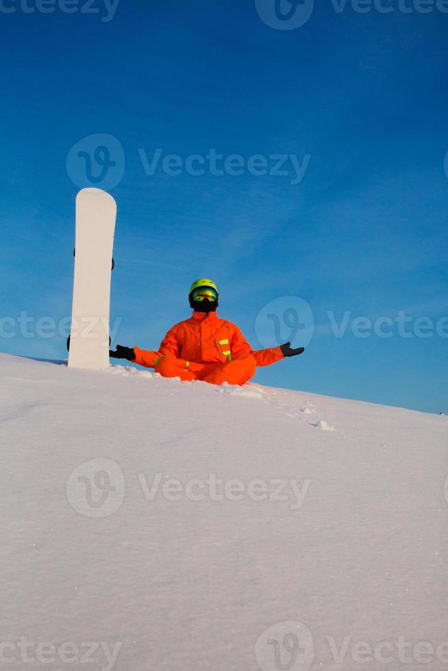 Snowboarder freerider with white snowboard sitting on the top of the ski slope photo