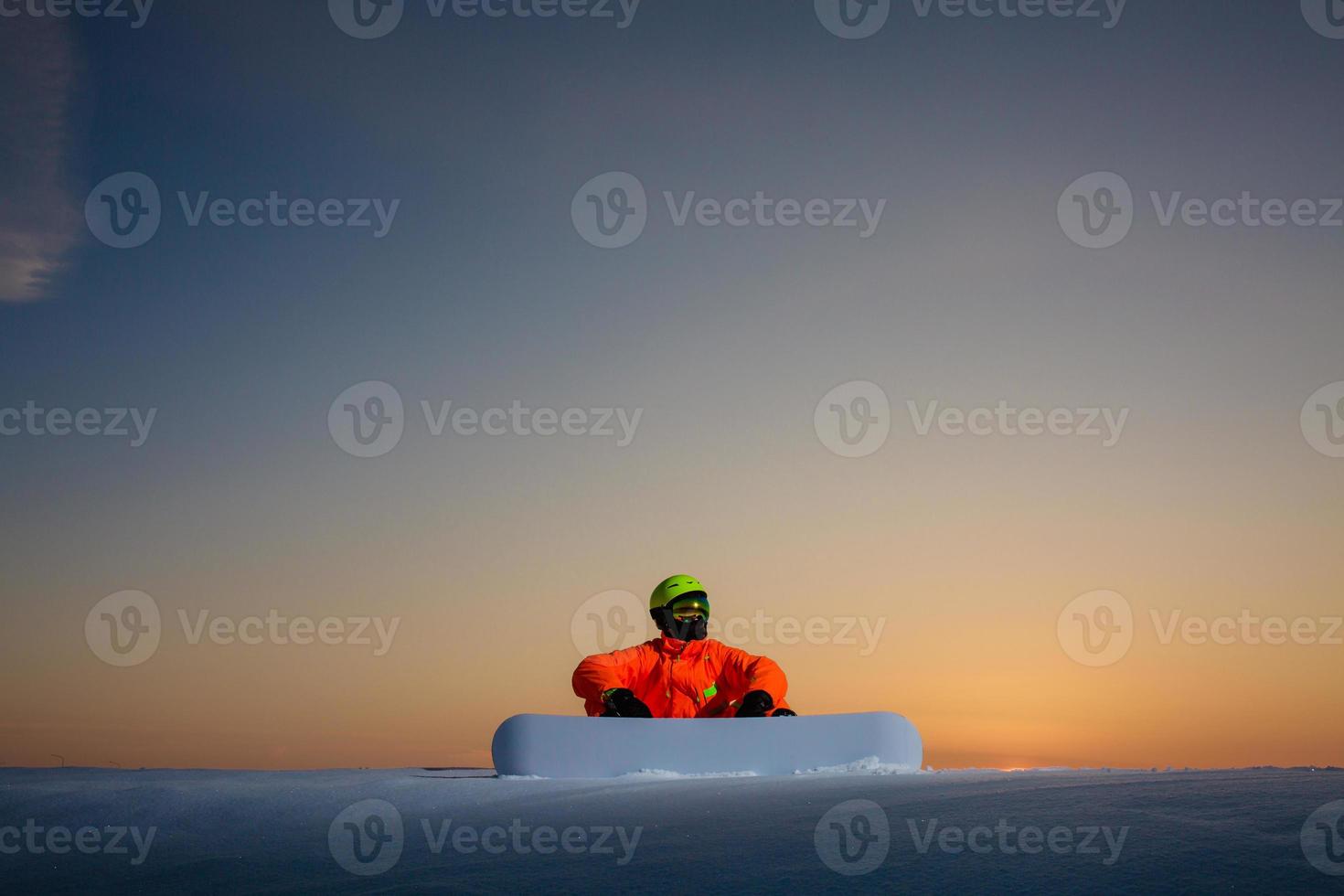 Snowboarder on the top of the ski slope at the background of beautiful sunset photo