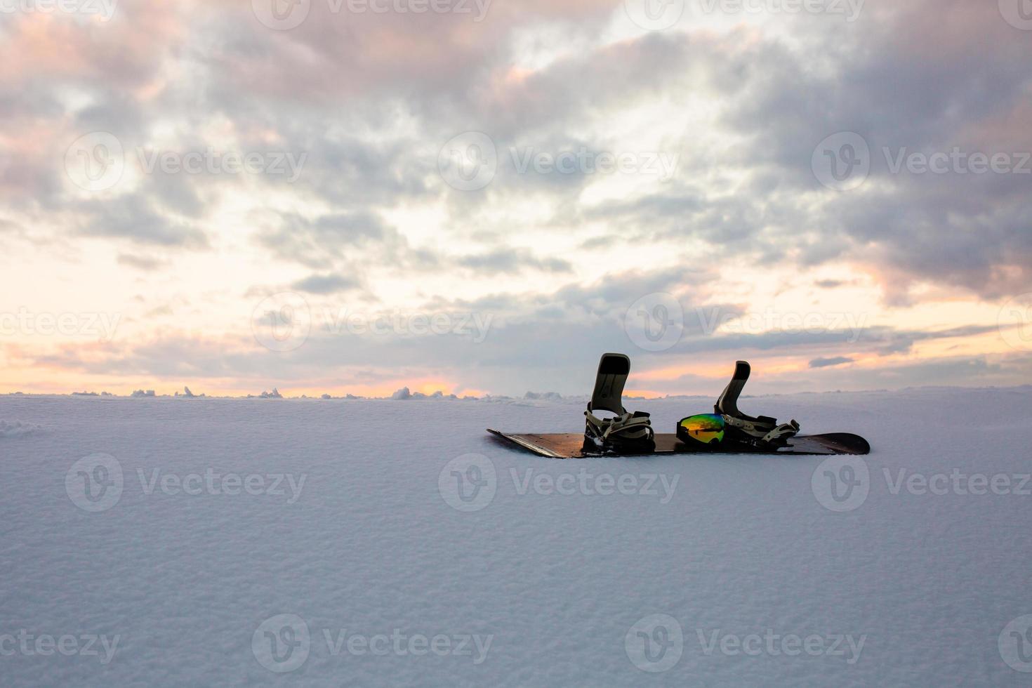 Textura en polvo y equipamiento para hacer snowboard al atardecer. foto