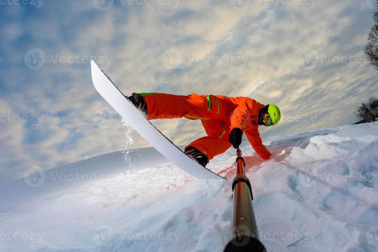 Snowboarder doing a trick and making a selfie photo