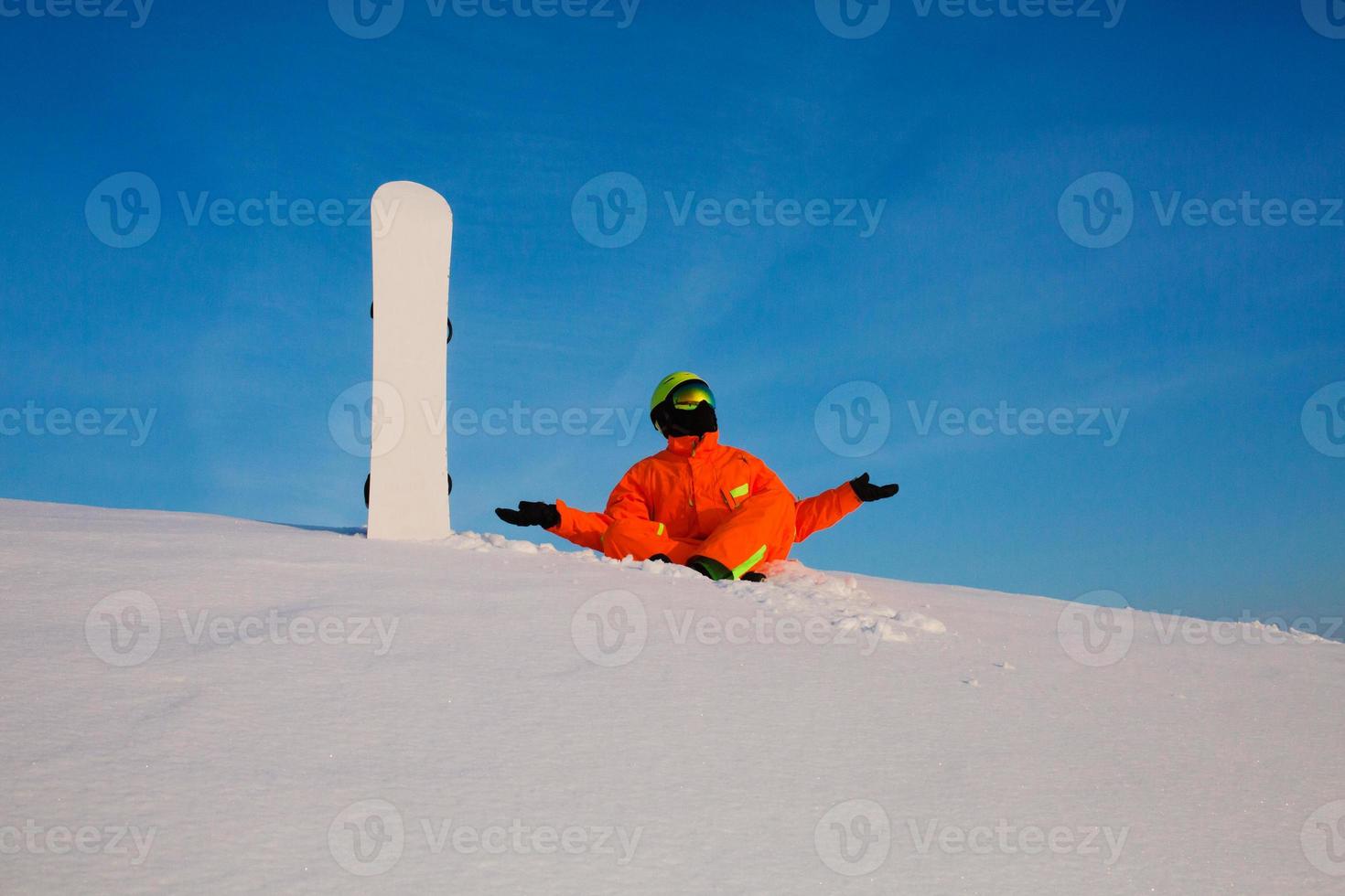 Snowboarder freerider with white snowboard sitting on the top of the ski slope photo