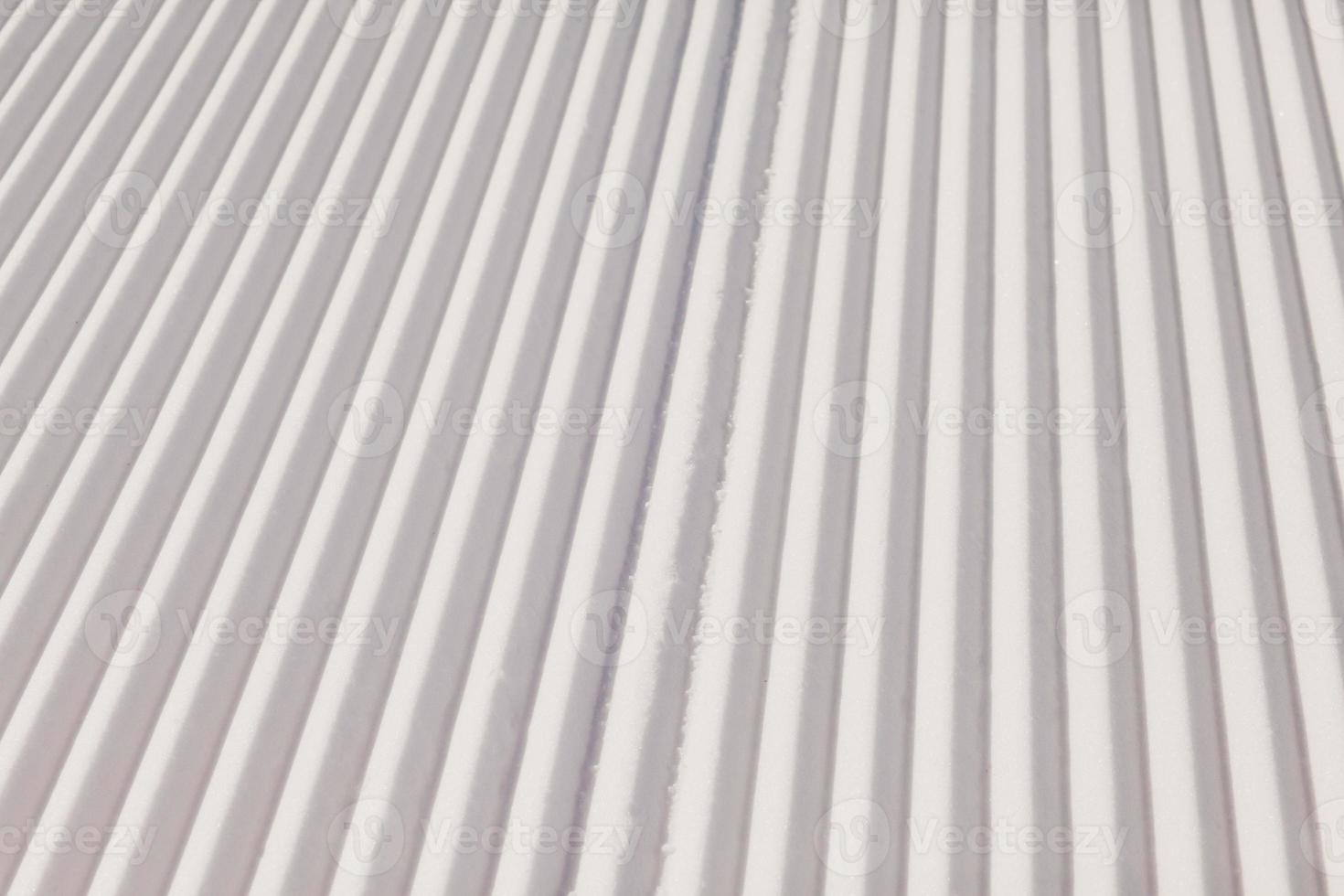 Texture of new groomed snow on empty ski slope photo