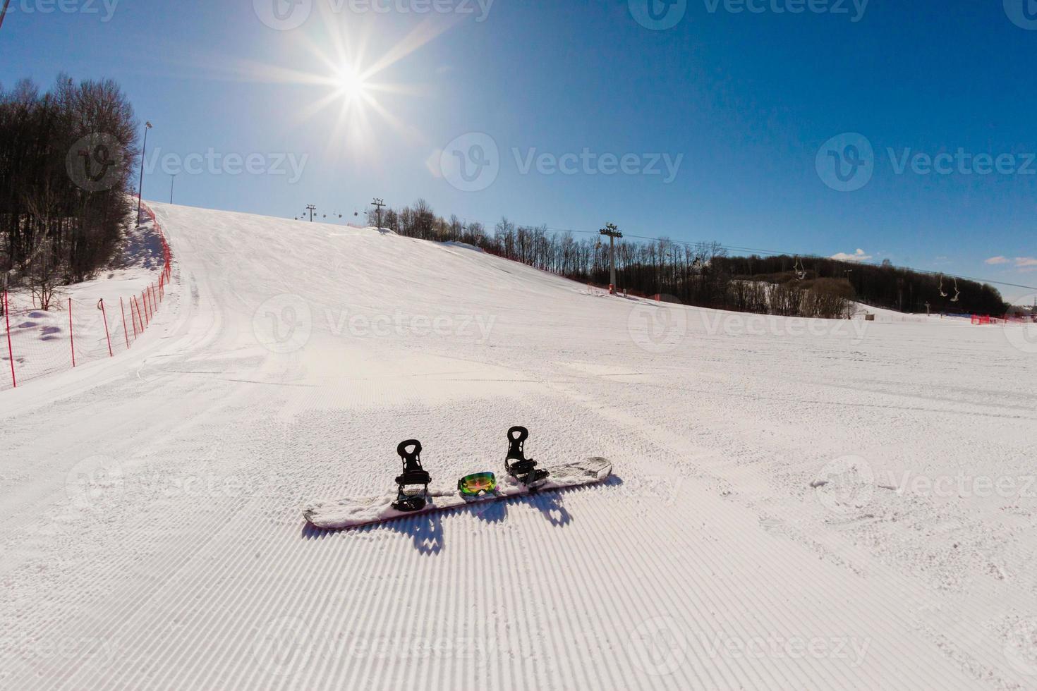 Bottom view on empty ski slope and equipment for snowboarding photo