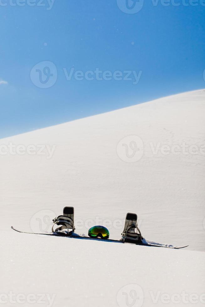 Snowboard and ski googles laying on a snow near the freeride slope photo