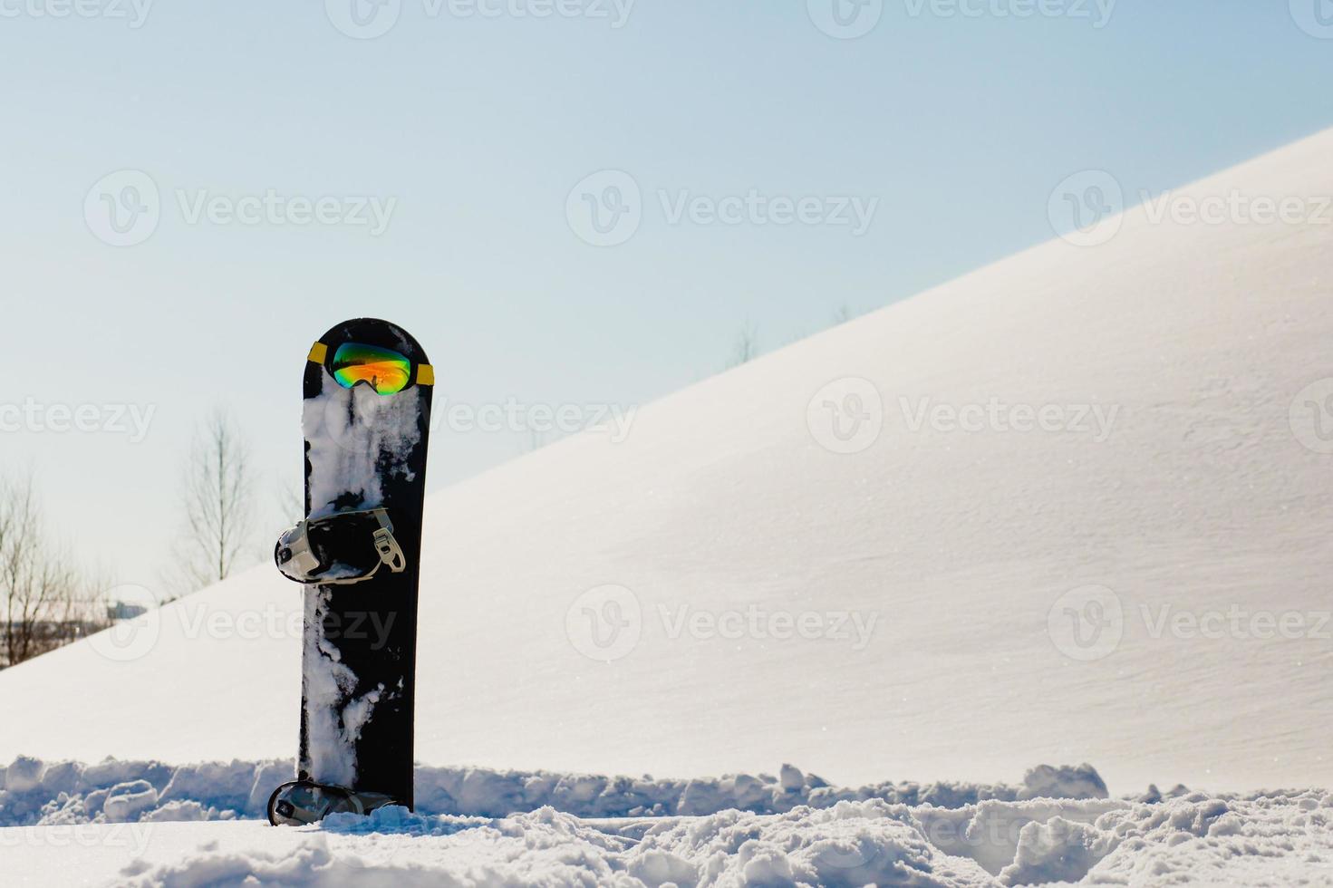 Gafas de snowboard y esquí tendido sobre la nieve cerca de la pista de freeride foto