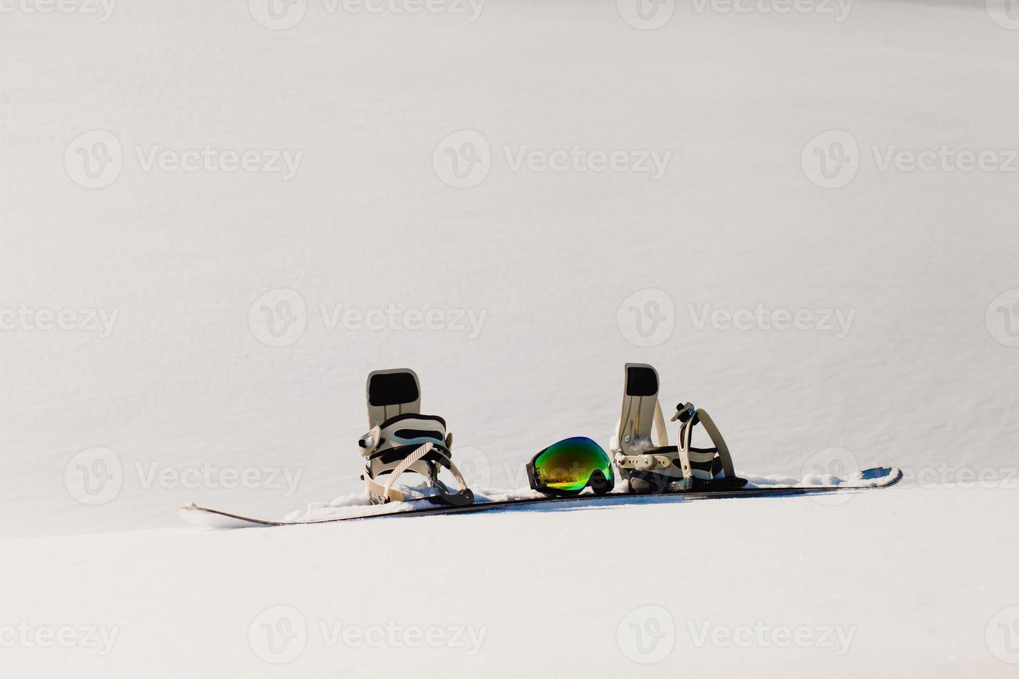 Gafas de snowboard y esquí tendido sobre la nieve cerca de la pista de freeride foto