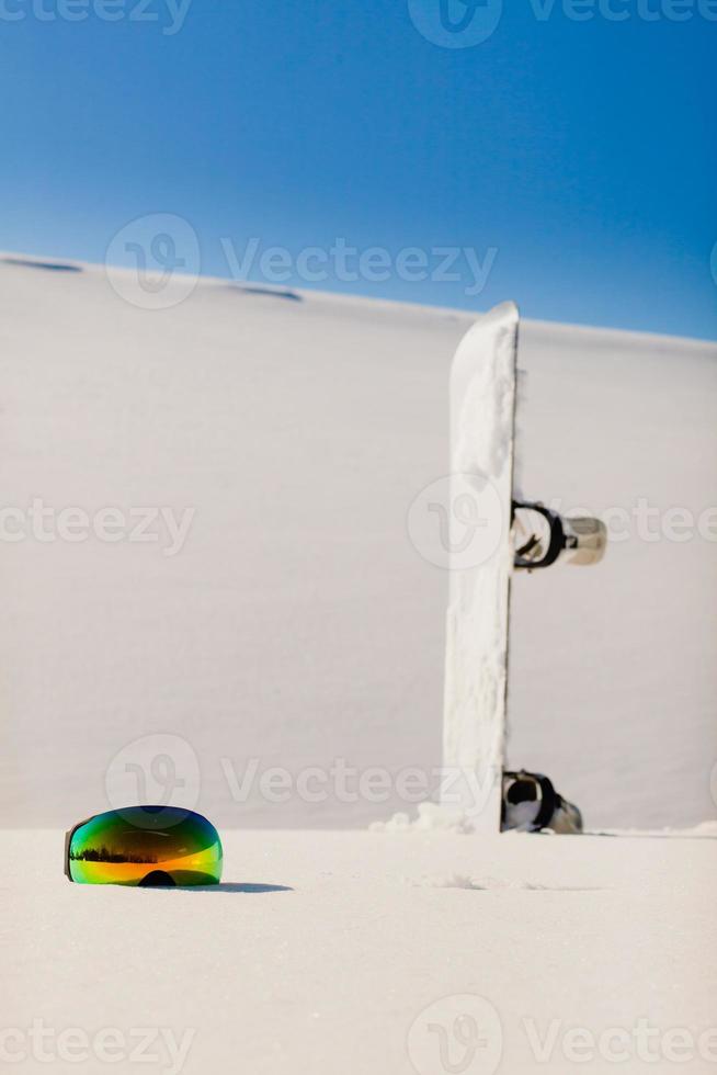 Snowboard and ski googles laying on a snow near the freeride slope photo