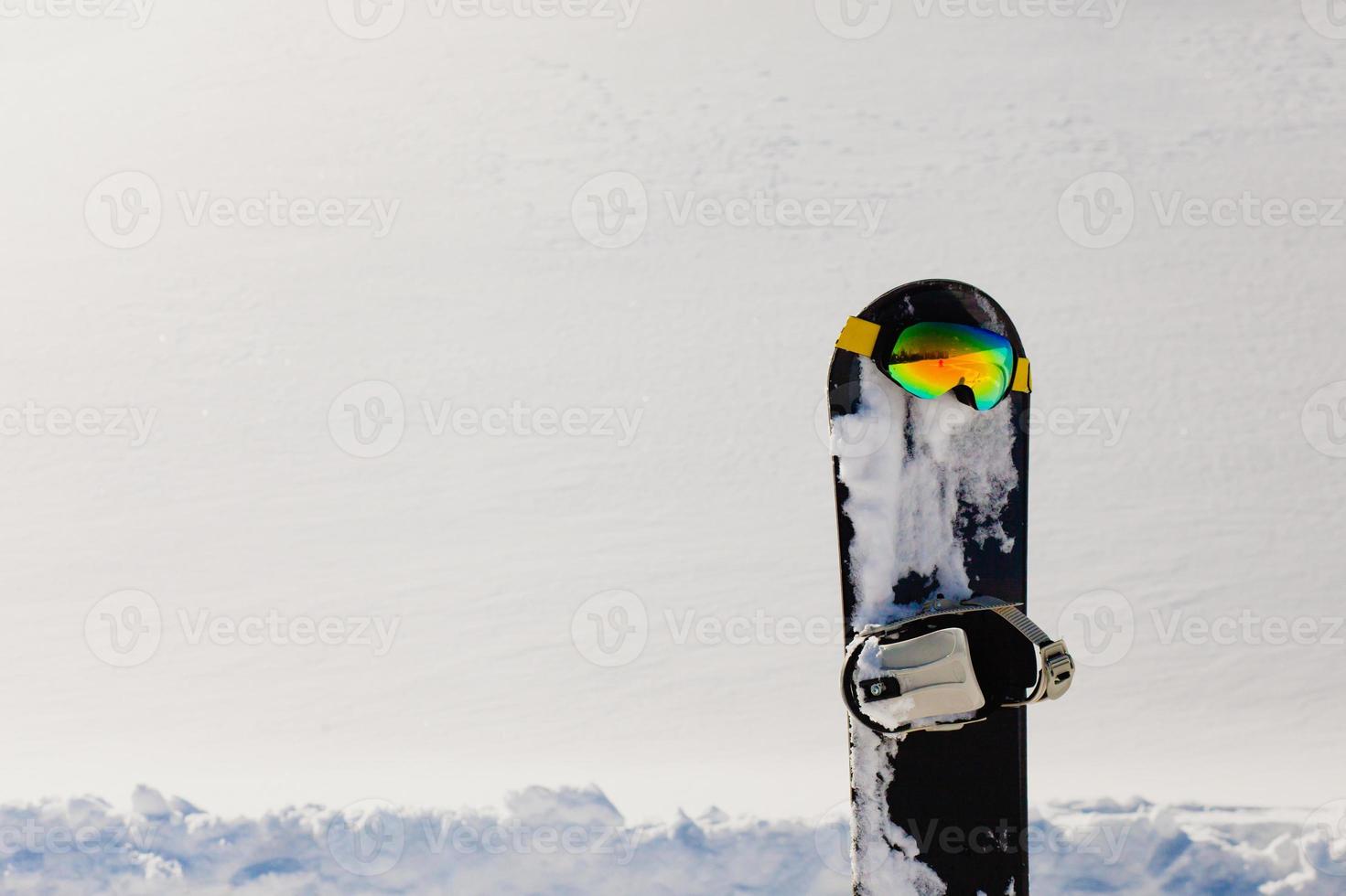 Snowboard and ski googles laying on a snow near the freeride slope photo