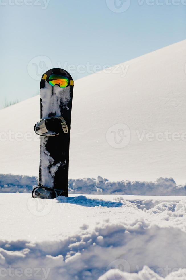 Snowboard and ski googles laying on a snow near the freeride slope photo