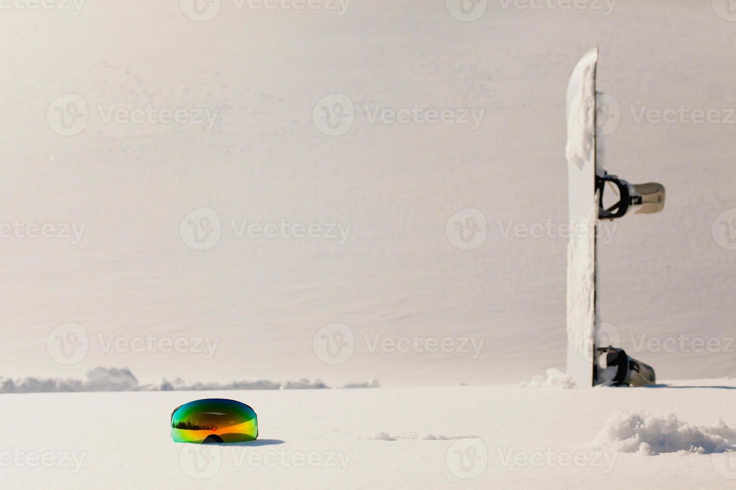 Gafas de snowboard y esquí tendido sobre la nieve cerca de la pista de freeride foto