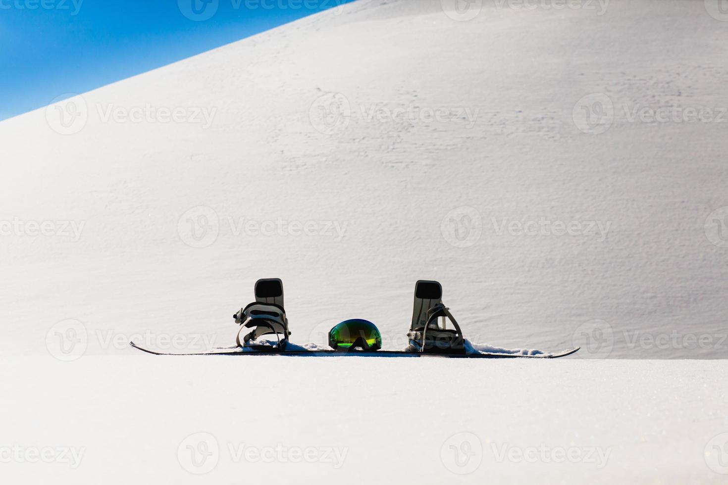 Gafas de snowboard y esquí tendido sobre la nieve cerca de la pista de freeride foto
