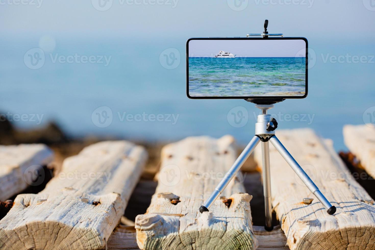 teléfono inteligente en trípode haciendo fotos y videos del paisaje marino
