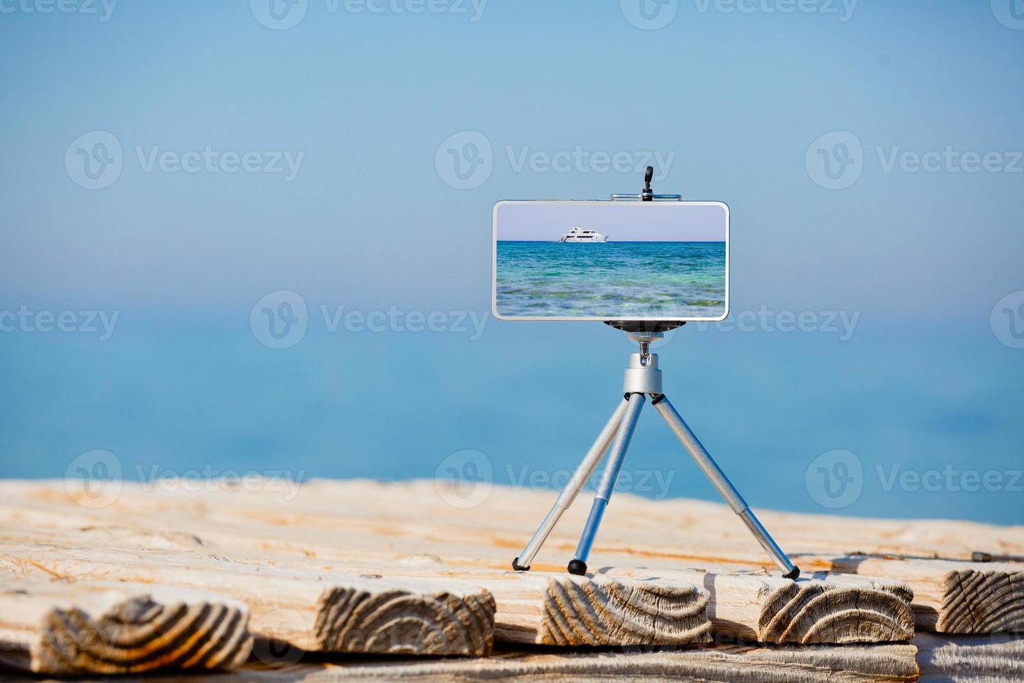 Smartphone on tripod making photo and video of sea landscape
