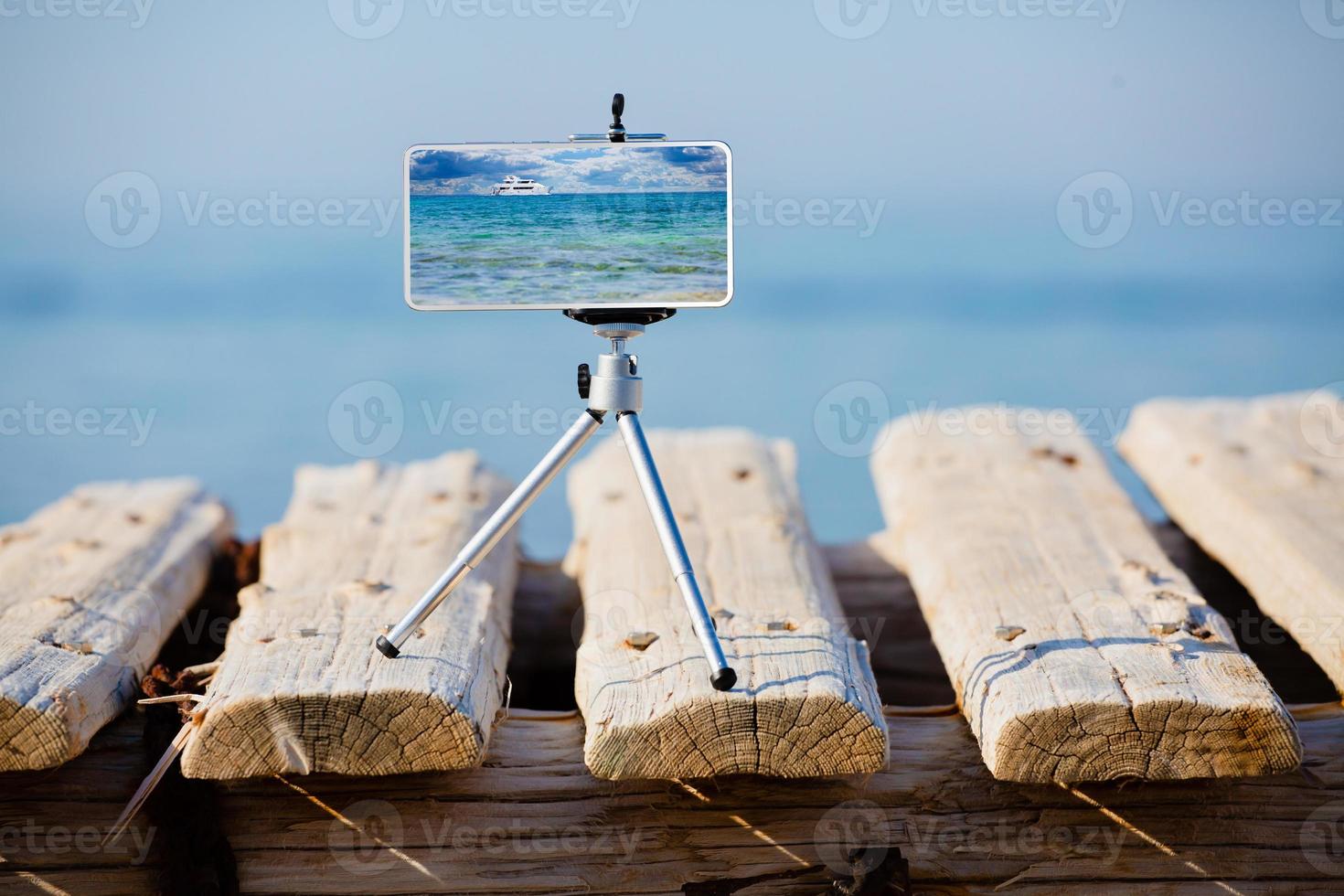 Smartphone on tripod making photo and video of sea landscape