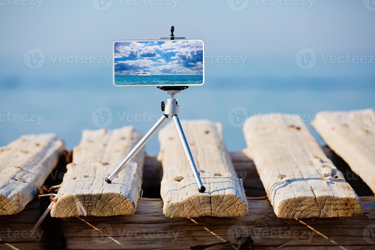 Smartphone on tripod making photo and video of sea landscape