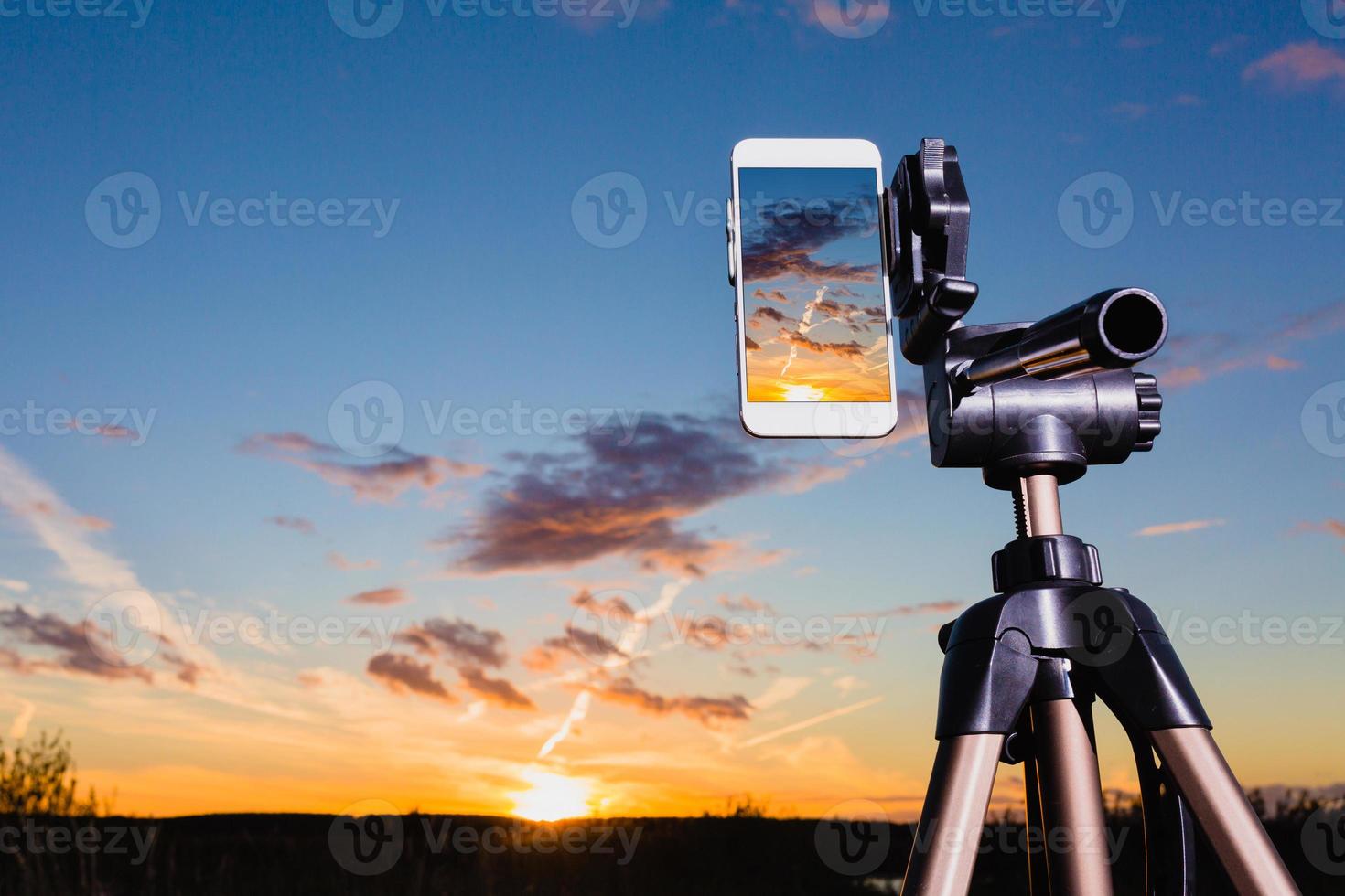 smartphone en trípode captura de imagen de la puesta del sol en modo vertical foto