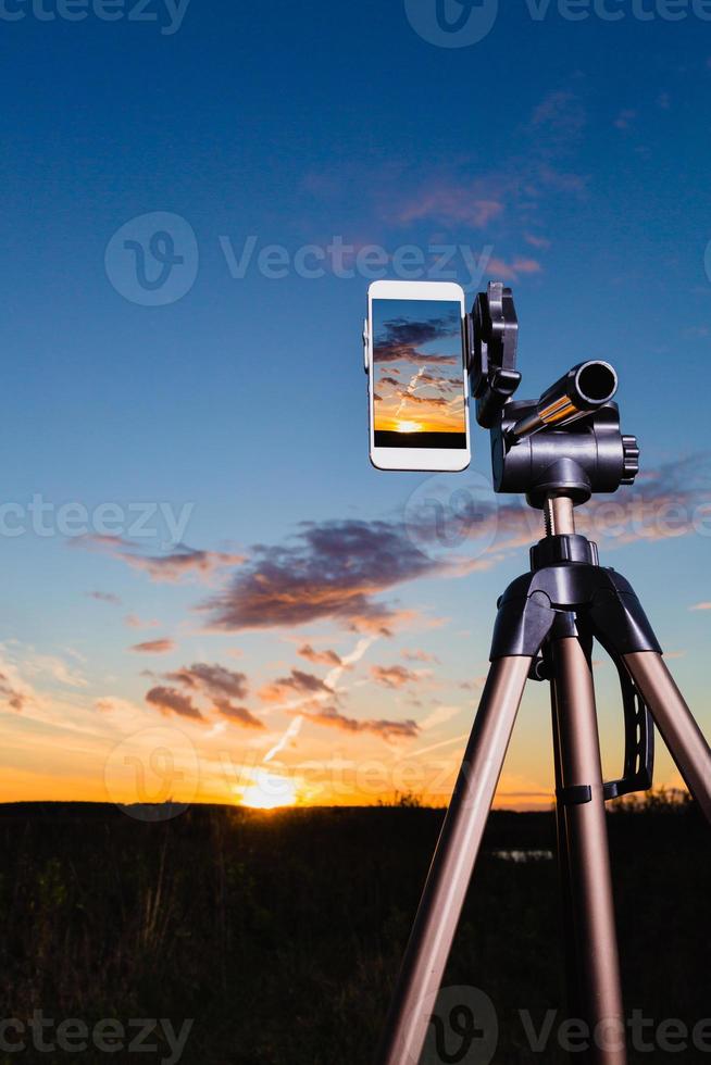 smartphone en trípode captura de imagen de la puesta del sol en modo vertical foto