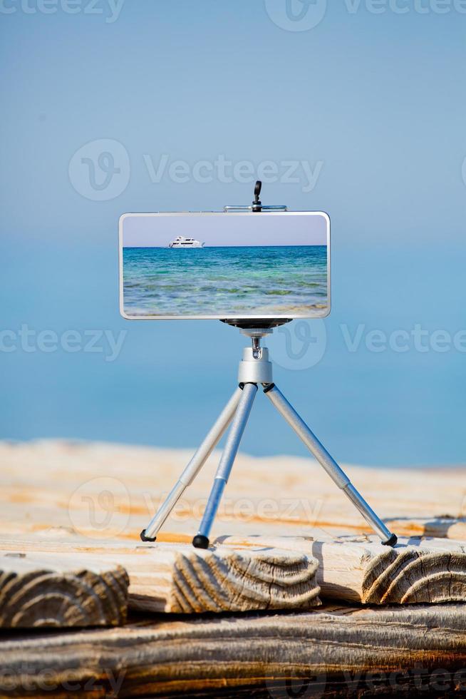 teléfono inteligente en trípode haciendo fotos y videos del paisaje marino