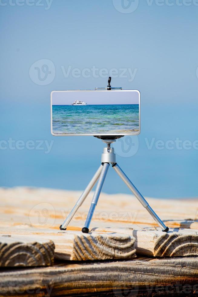 Smartphone on tripod making photo and video of sea landscape