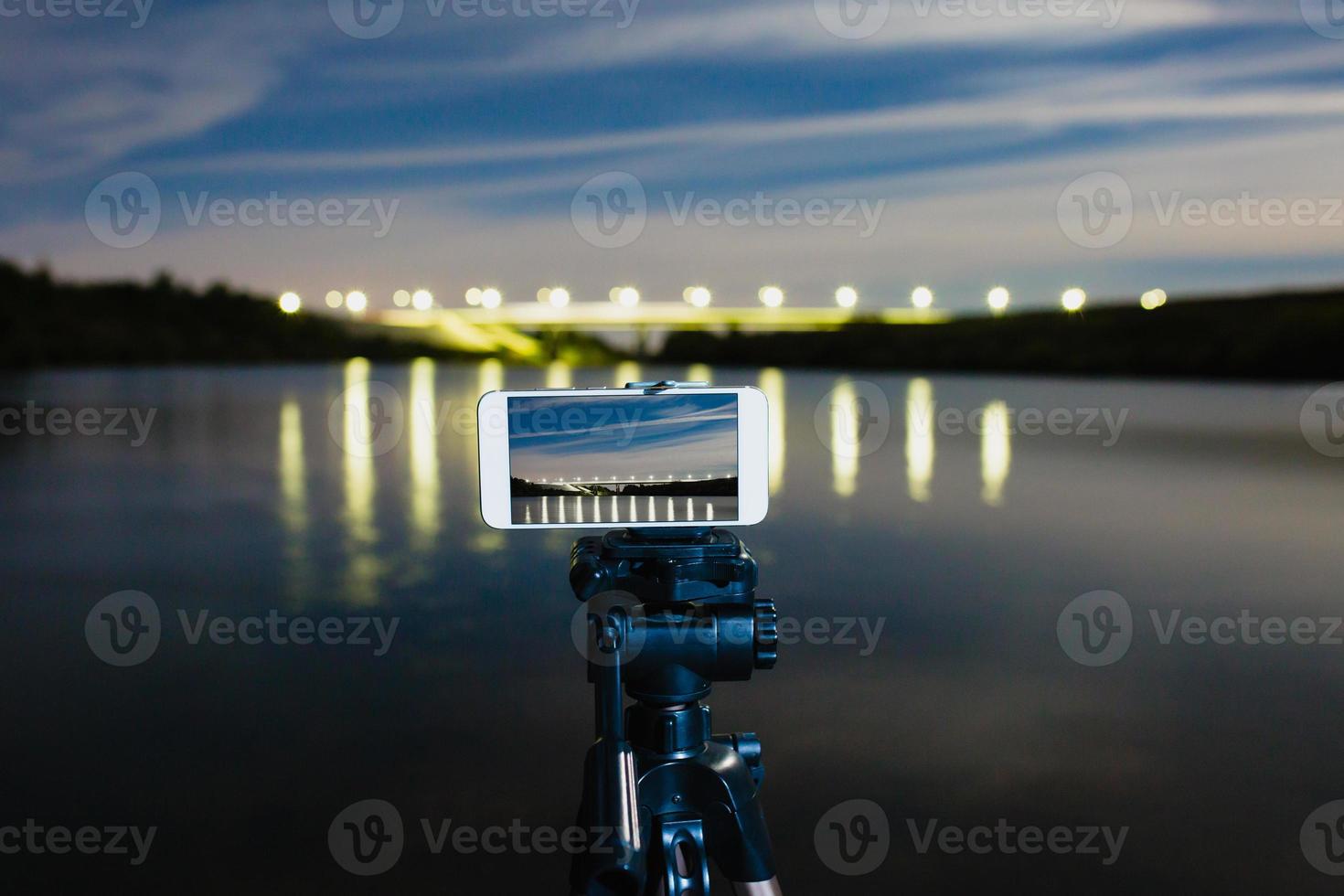 usando un teléfono inteligente como una cámara profesional en un trípode para capturar paisajes nocturnos foto