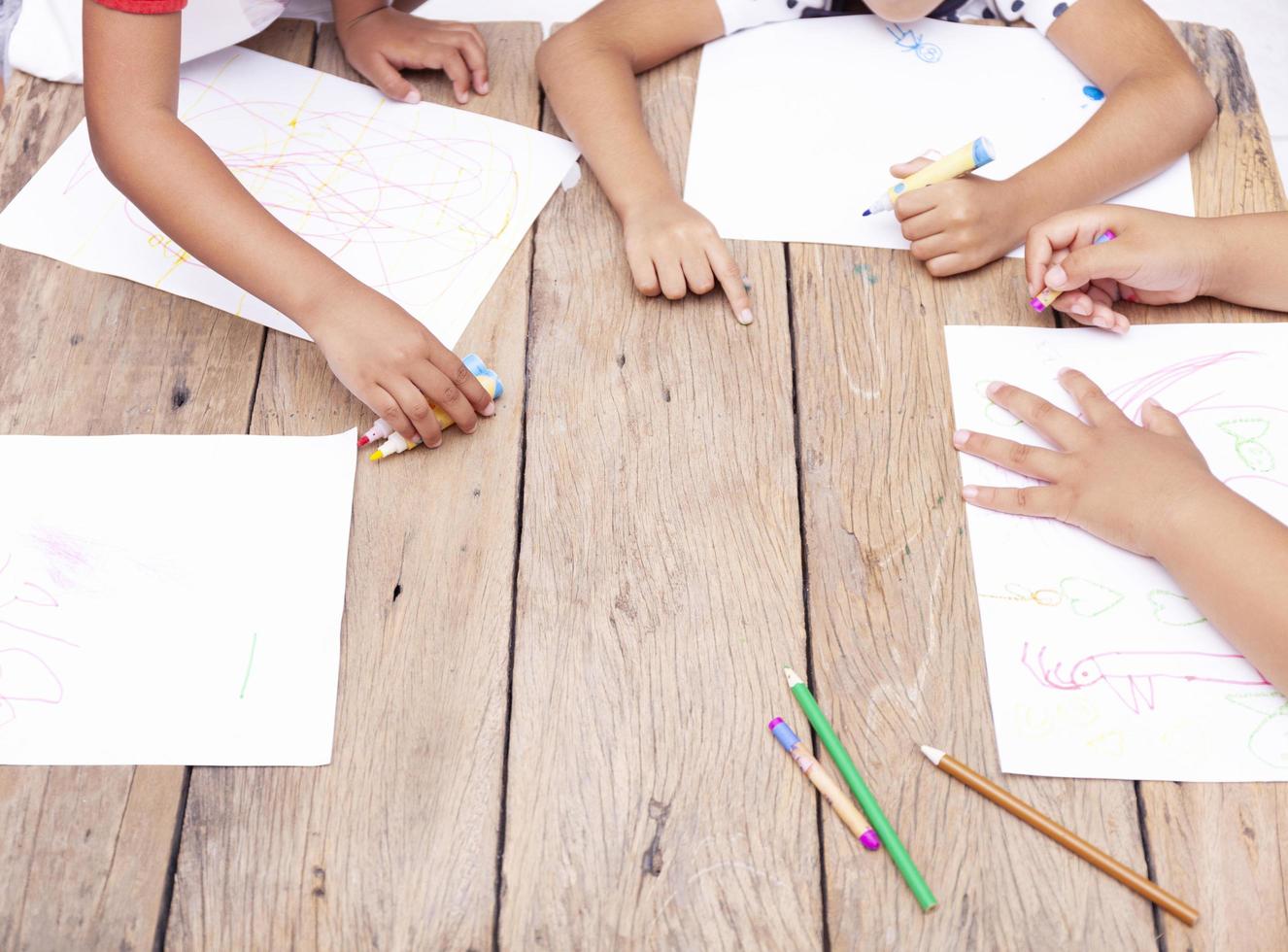 Children's hands drawing with colored pencils on wooden table,concept
