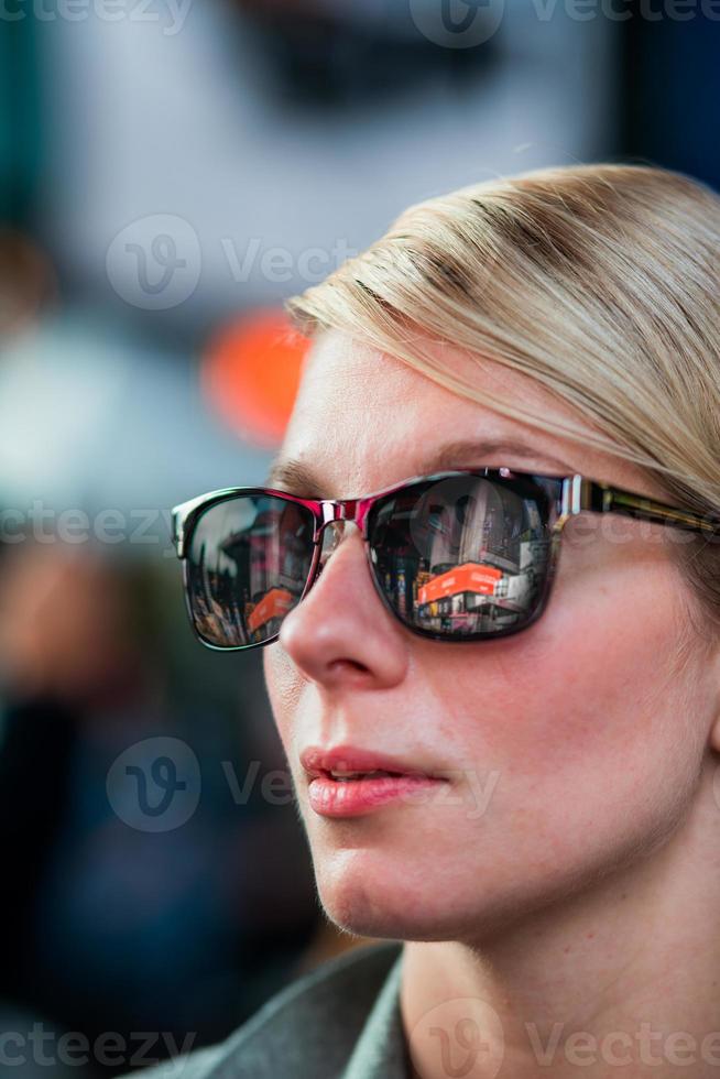 Mujer con reflejos de edificios de Time Square en gafas de sol por la noche, foto