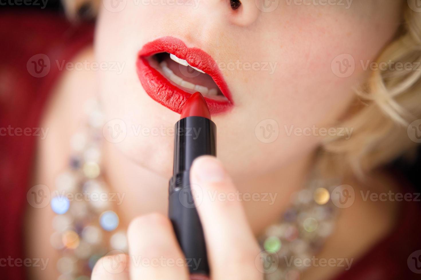 Señora poniendo lápiz labial - primer plano foto