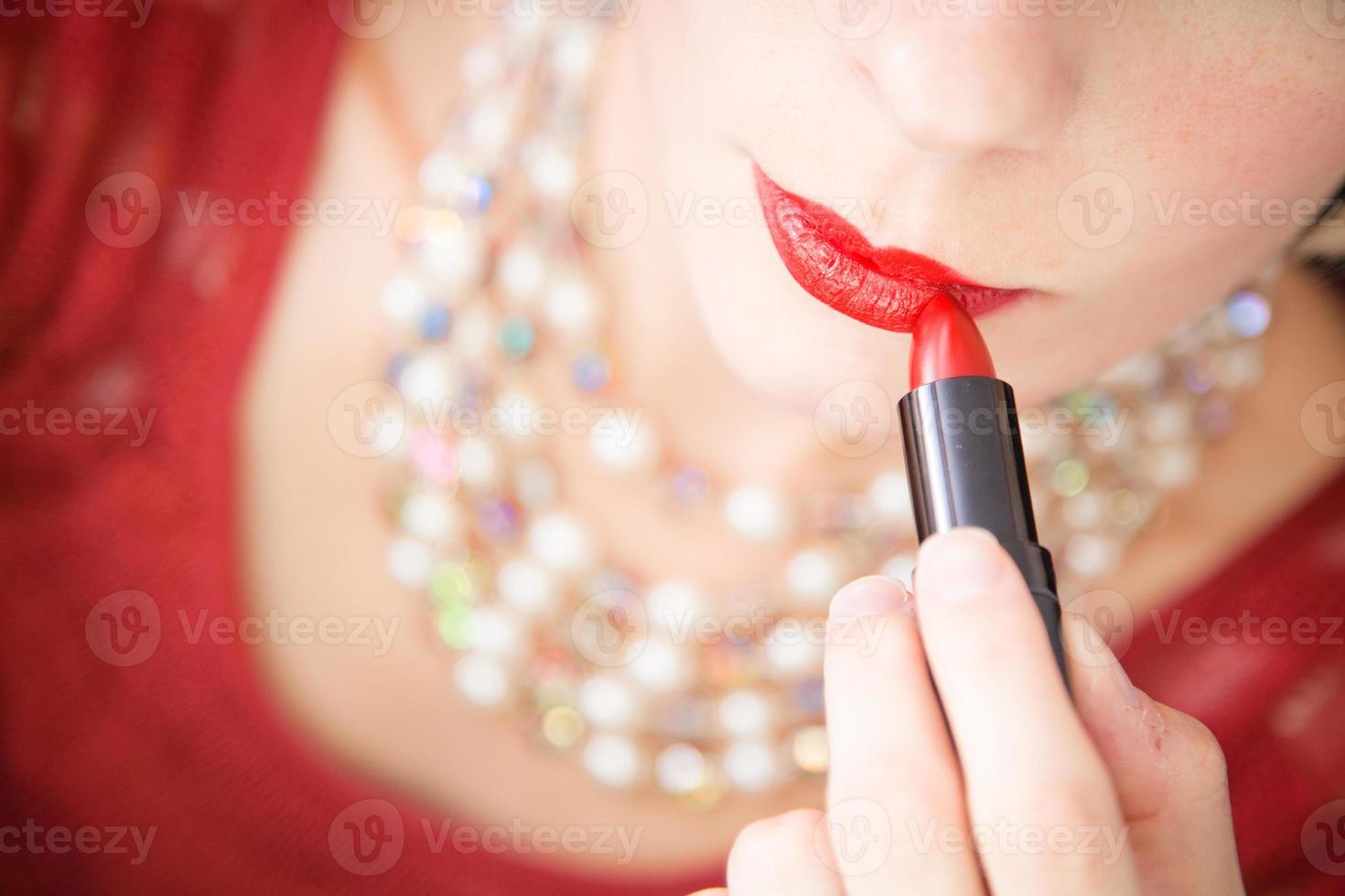 Lady putting lipstick - closeup photo