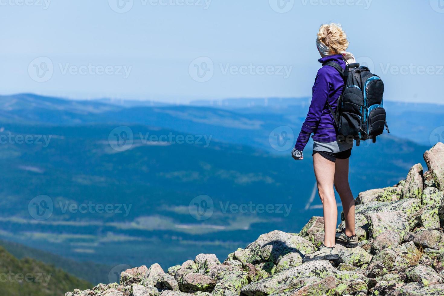 mujer joven mirando la vista desde la cima de la colina foto